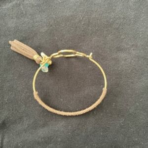 Gold tone quatrefoil bracelet with leather tassel and imitation gemstones